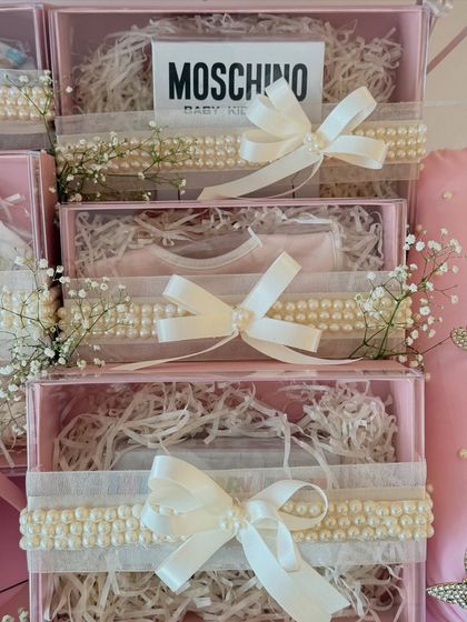 A close-up of the neatly arranged gift boxes inside the 'Baby M' hamper, each tied with a perfect pearl and satin bow.