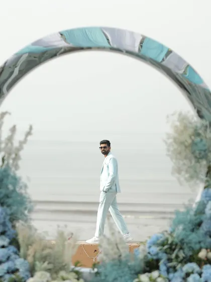 The groom looking sharp in his pastel blue suit, framed by the circular floral arch I designed for the brunch. The ocean in the background adds to the serene and stylish vibe.