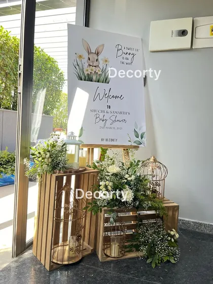 A rustic and charming entrance display for a bunny-themed baby shower, using wooden crates, birdcages, and fresh white flowers.