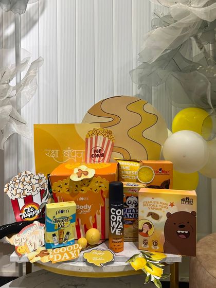 A fun, popcorn-themed Rakhi platter in bright yellow. This is perfect for the movie-loving sibling and is filled with snacks and self-care items.