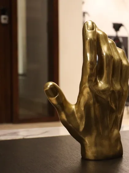 We often use sculpture and art to personalize a space. This close-up shows a brass hand sculpture, a powerful decorative object that adds a touch of personality and artistic flair to a tabletop.