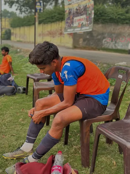 A moment of rest and preparation. A player adjusts his gear on the sidelines, getting ready to get back into the action.