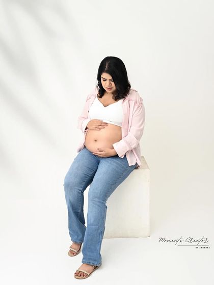 A simple and beautiful bare-bump shot. Dressed in casual jeans and an open shirt, the mom-to-be cradles her belly in this honest and tender portrait.