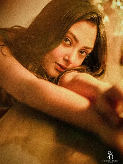 A warm, grainy portrait of actress Megha Chowdhury. The soft, golden light and her intimate gaze create a dreamy and cinematic feel.