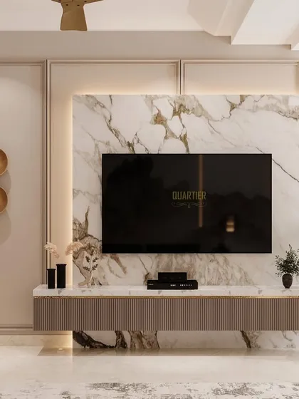 The TV unit in a guest bedroom, designed with a fusion of European and modern themes. The unit has fluted shutters and is set against a backdrop of marble texture and classic mouldings.