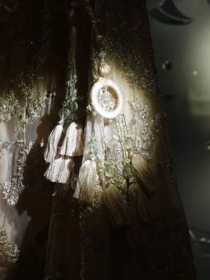 An artistic close-up of the bridal lehenga, with a spotlight highlighting the intricate embroidery and tassels. This detail shot showcases the craftsmanship and beauty of the bride's attire.