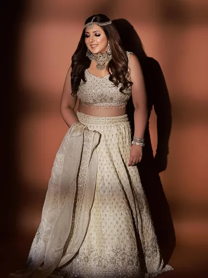 A full-length shot of this beautiful ivory lehenga. The intricate embroidery and the matching matha patti create a look of pure elegance, perfect for a modern bride.