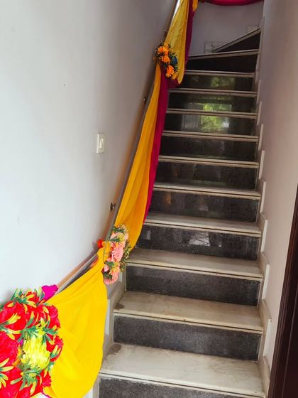 A simple and elegant staircase decoration with yellow and pink drapes and floral accents to carry the festive theme indoors.