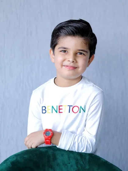 A clean, simple portrait of the birthday boy against a neutral background, highlighting his gentle smile. This shows the versatility of a birthday photoshoot.