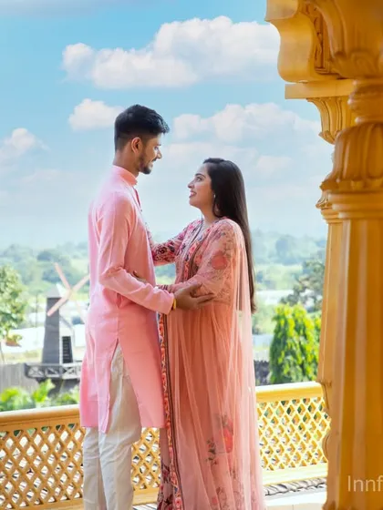 A tender moment between a couple on the balcony of our golden palace set, with the lush green landscape providing a beautiful contrast.