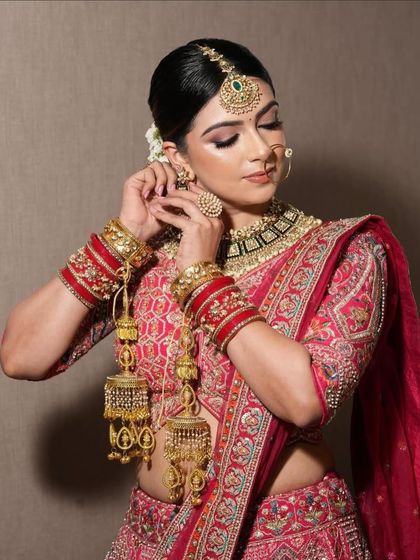 The complete bridal look is all about the details. This image shows how our red lehenga pairs beautifully with traditional kaleeras and bridal jewelry, highlighting the intricate sleeve embroidery.