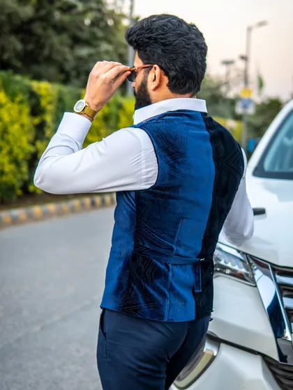 A stylish blue velvet waistcoat, shown from the back. The adjustable strap ensures a perfect fit, and the rich fabric adds a touch of luxury to any outfit.