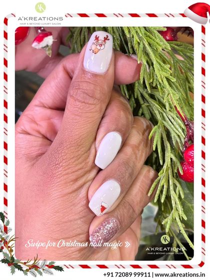 An elegant white Christmas manicure with a touch of sparkle, featuring a cute reindeer and a subtle Santa hat design on the accent nails.