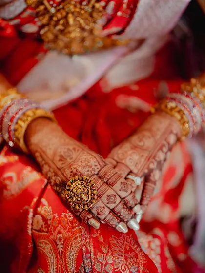 An intimate shot of the bride's hands, her fingers interlaced, showing the beautiful mehendi on her palms and fingers.