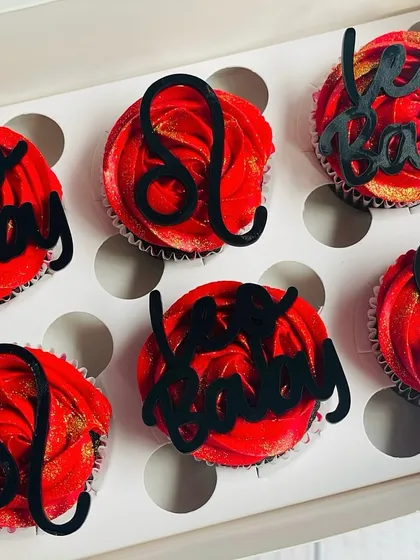 I love making birthdays personal with these custom zodiac cupcakes. This set for a Leo features rich chocolate cupcakes with bold red buttercream, a hint of gold glitter, and striking black acrylic toppers of the Leo symbol and "Leo Baby" text.