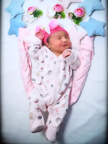 A happy, sleepy stretch from a baby girl in her cute onesie, surrounded by pink and blue stars. These natural movements make for the most heartwarming photos.