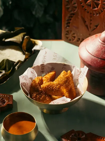 Fried snacks in a brass bowl, styled with traditional decor. The lighting and props create a warm, inviting atmosphere.