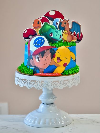 Gotta catch 'em all. This Pokémon-themed cake is perfect for any fan, featuring Ash, Pikachu, and other favorite characters as edible toppers on a vibrant blue and green cake.