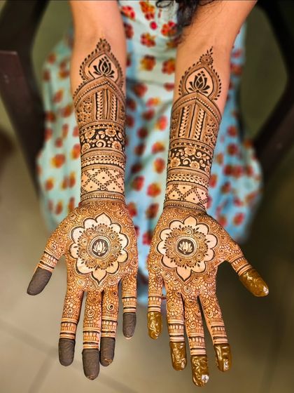 A stunning mandala design with a lotus at its center, surrounded by intricate patterns on the fingers and arm.