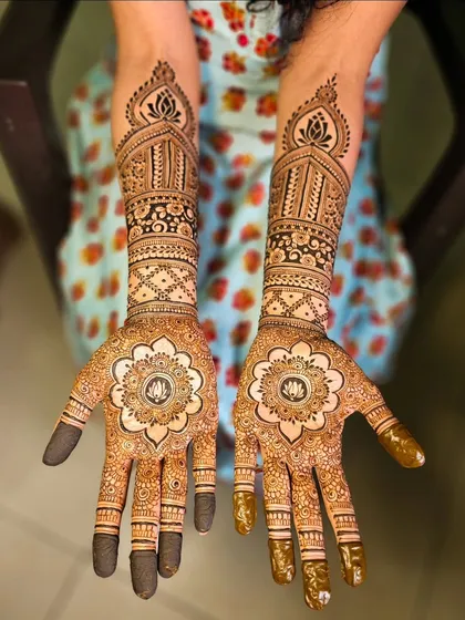 A stunning mandala design with a lotus at its center, surrounded by intricate patterns on the fingers and arm.