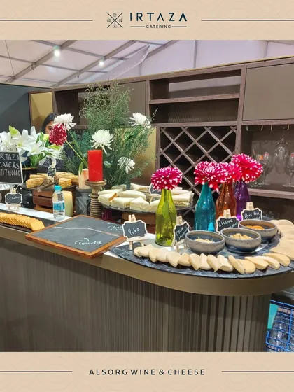 A stylish bar and appetizer station setup for a wine and cheese event. The curved counter, wine rack, and colorful decor create a sophisticated space for guests to mingle.