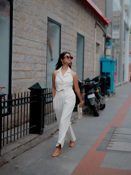 A full-length shot of a model walking down the street in a chic all-white outfit. This captures a natural, in-motion look that is perfect for lifestyle and fashion content.