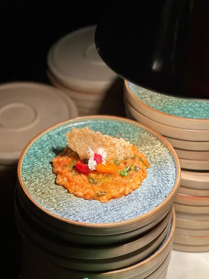 A stack of our beautiful, rustic plates, each holding a serving of flavourful risotto. We ensure that every single plate that leaves our kitchen is perfect.