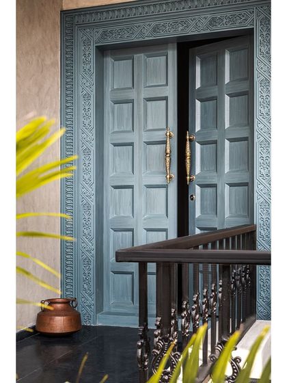 The main door of Prangan is a statement piece, with intricate carvings and a unique steel blue finish that sets the tone for the entire home.