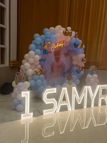 This was a lovely Cocomelon-inspired setup for Samyra's first birthday. It features a personalized backdrop, a pastel balloon arch, and large illuminated letters for her name.