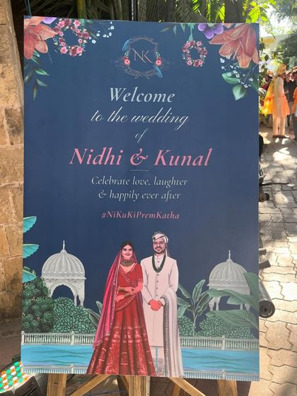 Elevate your wedding entrance with a beautifully crafted welcome board. This one features a custom illustration of the couple in their wedding attire against a backdrop of their venue, complete with their wedding hashtag.