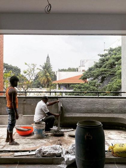 Workers constructing a built-in concrete bench on a balcony. We often design custom seating and planters directly into the structure to create a seamless and integrated living experience.