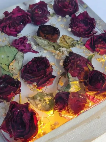 This resin block preserves a client's bouquet of roses, turning them into a permanent piece of art. The wooden base with an LED light makes the flowers glow beautifully.