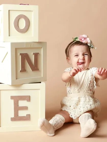 A cheeky little tongue-out expression from the birthday girl. Her personality shines in this fun first birthday portrait.