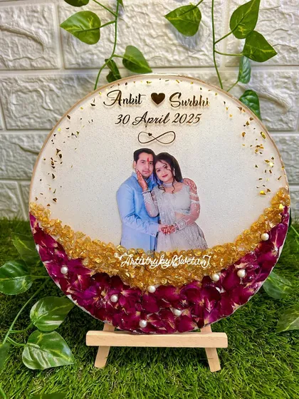 The completed circular photo frame, featuring preserved purple flowers and a couple's cherished picture. It's an affordable way to turn a memory into a beautiful display piece.