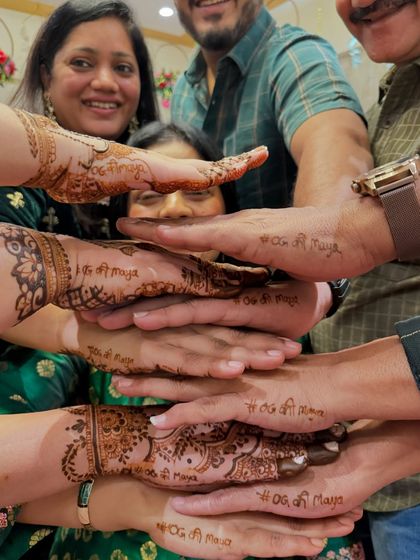 A creative shot of the family showing the wedding hashtag written on their hands. A fun way to personalize the guest mehendi.