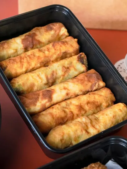 Freshly prepared Spinach and Chicken Cigars, neatly packed and ready for delivery as part of a larger Iftar box.