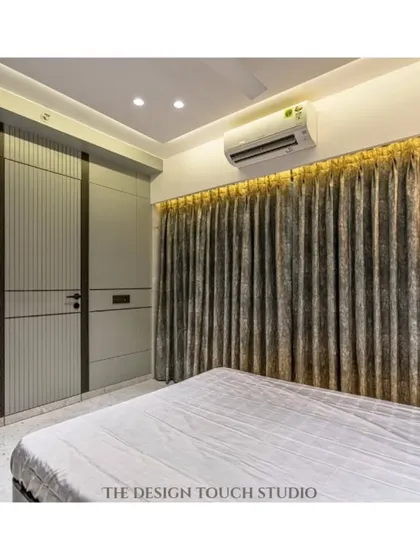 A view of the room showing the elegant curtains and the custom wardrobe design. The lighting is carefully planned to enhance the warm and inviting ambiance.