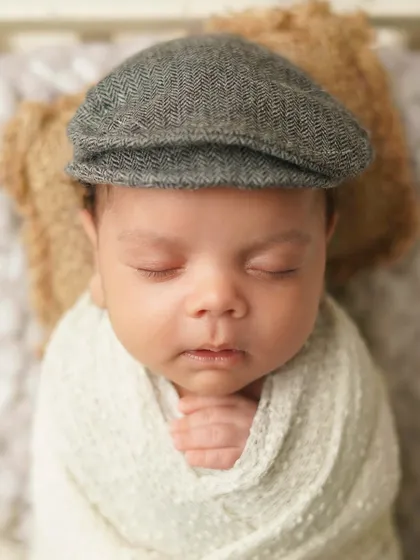 A close-up of a newborn wearing a dapper newsboy cap. This vintage accessory adds a touch of old-world charm to his portrait.