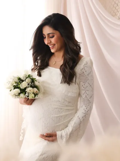 An angelic maternity shoot look. The soft, natural makeup complements the ethereal white dress and enhances the mother's unmatched glow.