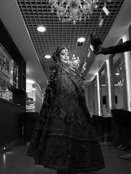 A full-length black and white shot showing the entire silhouette of the bride in the salon. It captures the grandeur of the complete bridal attire and the confidence of the bride.