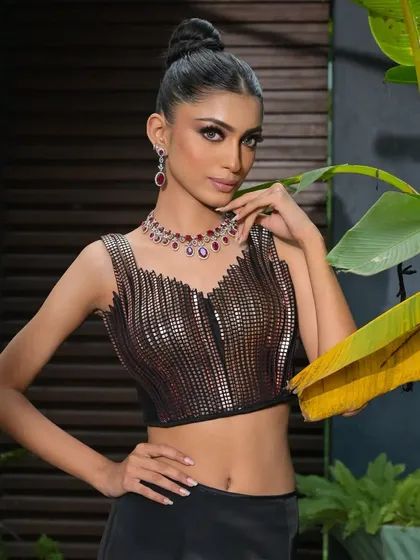 A full-body shot where the clean top-knot provides a perfect counterpoint to the metallic, textured top and flowing skirt.
