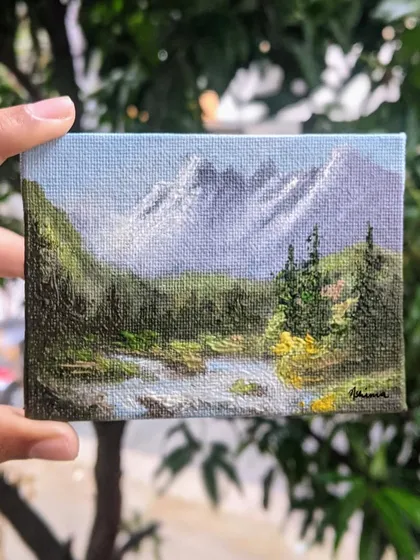 Holding this 3x4 inch canvas lets you see the details up close. I used different shades of green to paint the forest and added texture to the water to make this miniature landscape feel alive.