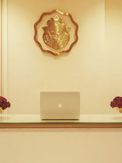 Even small details are thoughtfully considered. The reception desk features a simple glass top with elegant floral arrangements and a brass Ganesha idol, setting a tone of grace and tradition.