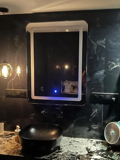 A closer look at the vanity area in a black-themed bathroom. The LED mirror provides excellent task lighting, while the open shelving and countertop offer space for daily essentials.
