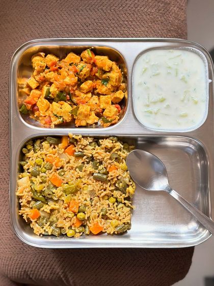 A satisfying meal of vegetable pulav, paneer bhurji, and cucumber raita, perfect for a healthy and flavorful lunch.