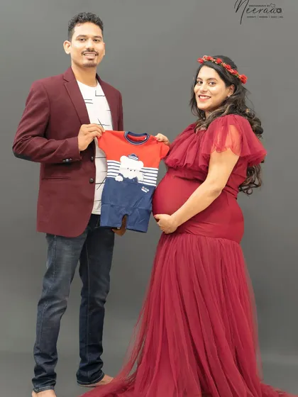 "Look what we're waiting for!" Holding up a tiny baby outfit is such a sweet and tangible way to celebrate the little one on the way. It makes the moment feel so real and exciting.