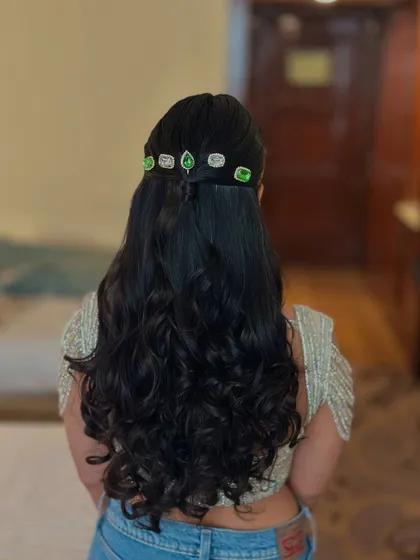 A simple half-up style with soft curls, made unique with a line of green and white stone accessories.