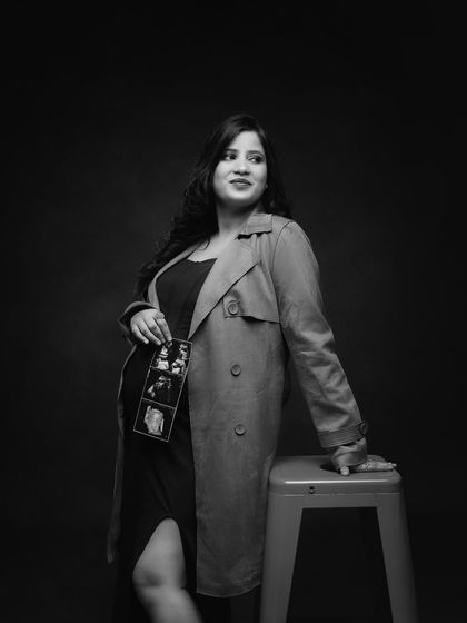 A stylish black and white portrait with a trench coat. This shot has a classic, cinematic feel, and the ultrasound pictures add a personal story.