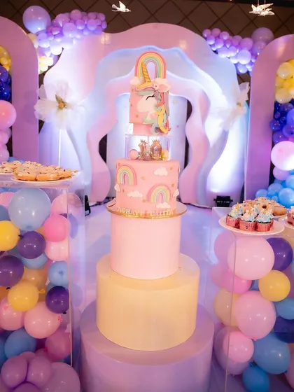 The unicorn cake displayed on a custom pedestal, surrounded by balloons and desserts.