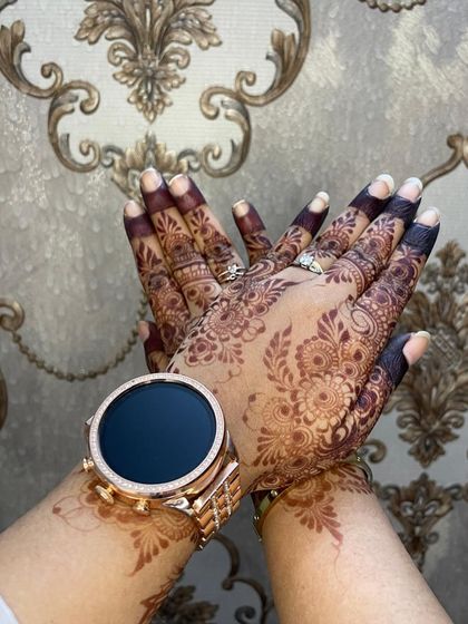 A close-up of the developed henna stain on the back of the hands, showing the deep color on the fingers.